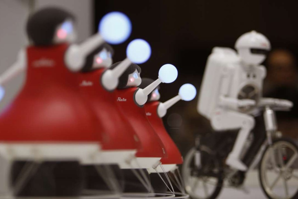 Robot cheerleaders developed by Murata Manufacturing Co. perform synchronised dancing as bicyclist robot "Murata Seisaku-kun", or Murata Boy is seen in the background during the annual CEATEC Japan advanced technologies show in Chiba last October. Photo: Koji Ueda/AP