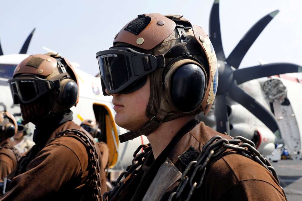 US Navy ground personnel watch as a F18 fighter jet takes off on aircraft carrier USS Carl Vinson during a routine exercise in the South China Sea. Photo: Reuters
