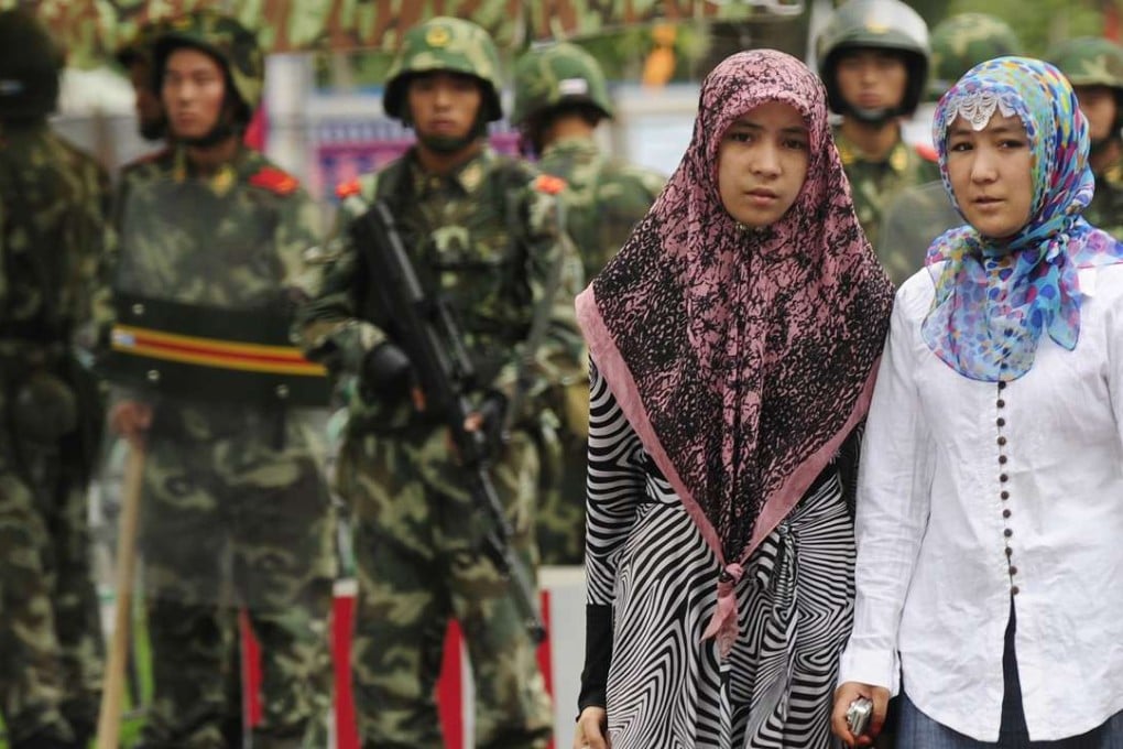 Two Uygur women walk past paramilitary policemen standing guard outside the Grand Bazaar in Urumqi, Xinjiang. Photo: AFP