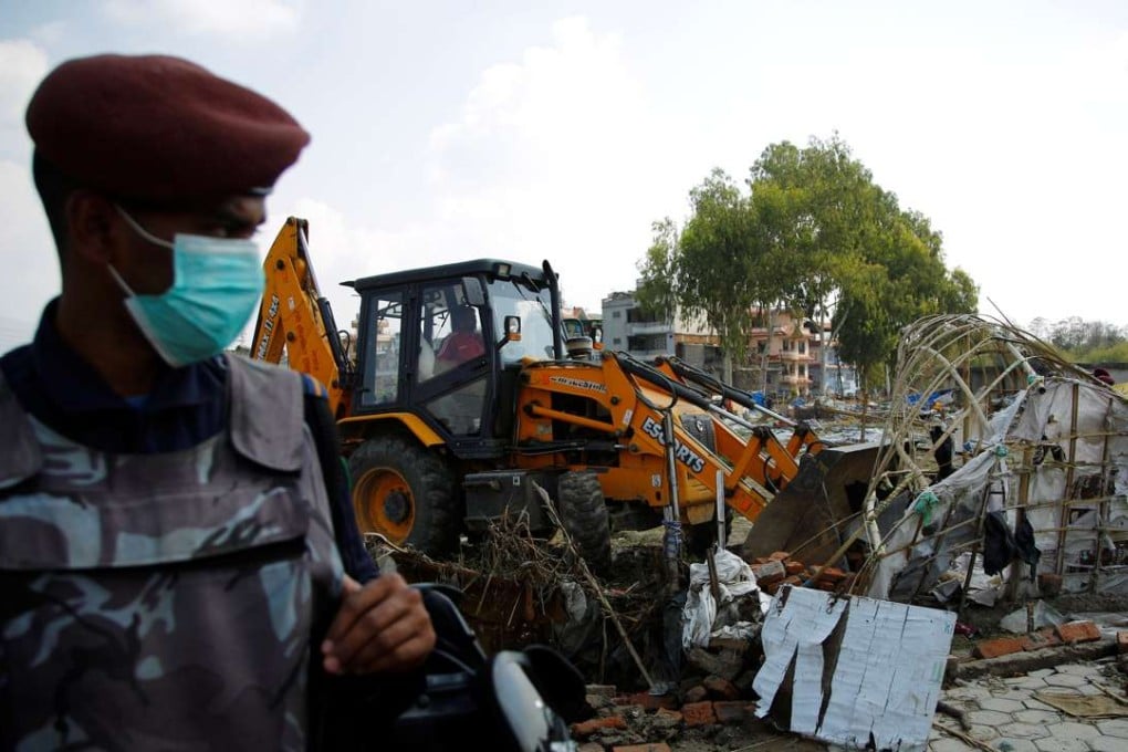 A Nepalese police officer stands guard as makeshift shelters are being demolished at the displacement camp for earthquake victims in Kathmandu. Photo: Reuters