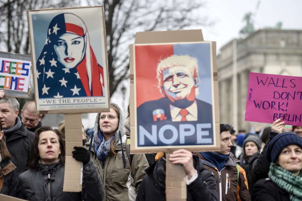 A protester with a portrait of US President Donald Trump. Photo: EPA