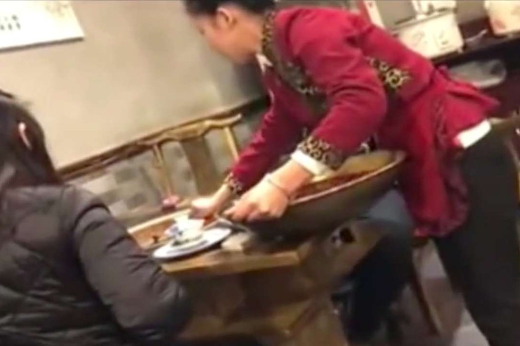 A waitress is shown clearing away leftover hotpot oil in footage from the TV report. Photo: Handout