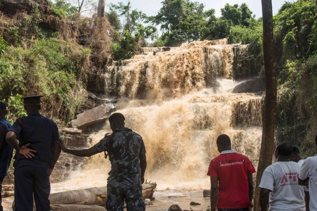 Police and volunteers stand in front of the waterfalls in Kintampo, where 20 people were killed on Sunday when a giant tree collapsed on them. Photo: AFP