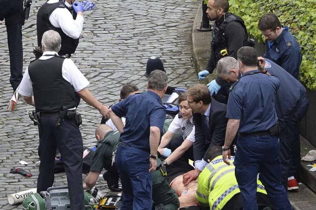 Conservative Member of Parliament Tobias Ellwood (centre, in suit) prvides first aid to police officer Keith Palmer, who was stabbed in the terrist attack outside the UK parliament in London. Palmer did not survive. Photo: AP