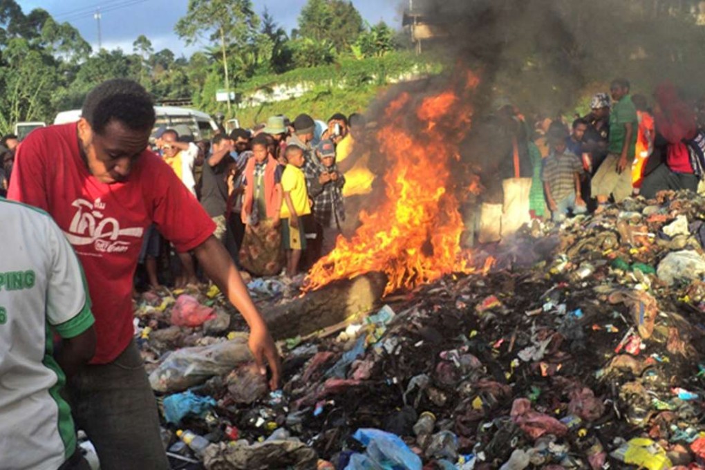 A crowd watching after a young mother accused of sorcery was set alight with petrol on a pile of rubbish topped with car tyres in 2013. Photo: AFP