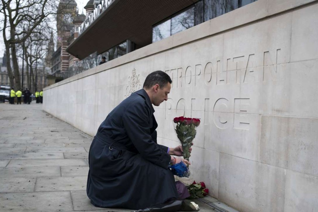 A man lays flowers outside New Scotland Yard in central London. Scotland Yard said police have made seven arrests in raids carried out over night in Birmingham, London and elsewhere after the terror attack in the Westminister Palace grounds and on Westminster Bridge that left three people dead, including the attacker. Photo: EPA