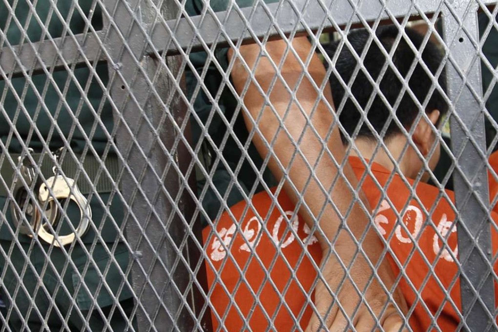 Cambodian Oeuth Ang is guarded by a police officer in a truck as he arrives at the Municipal Court in Phnom Penh. Photo: EPA