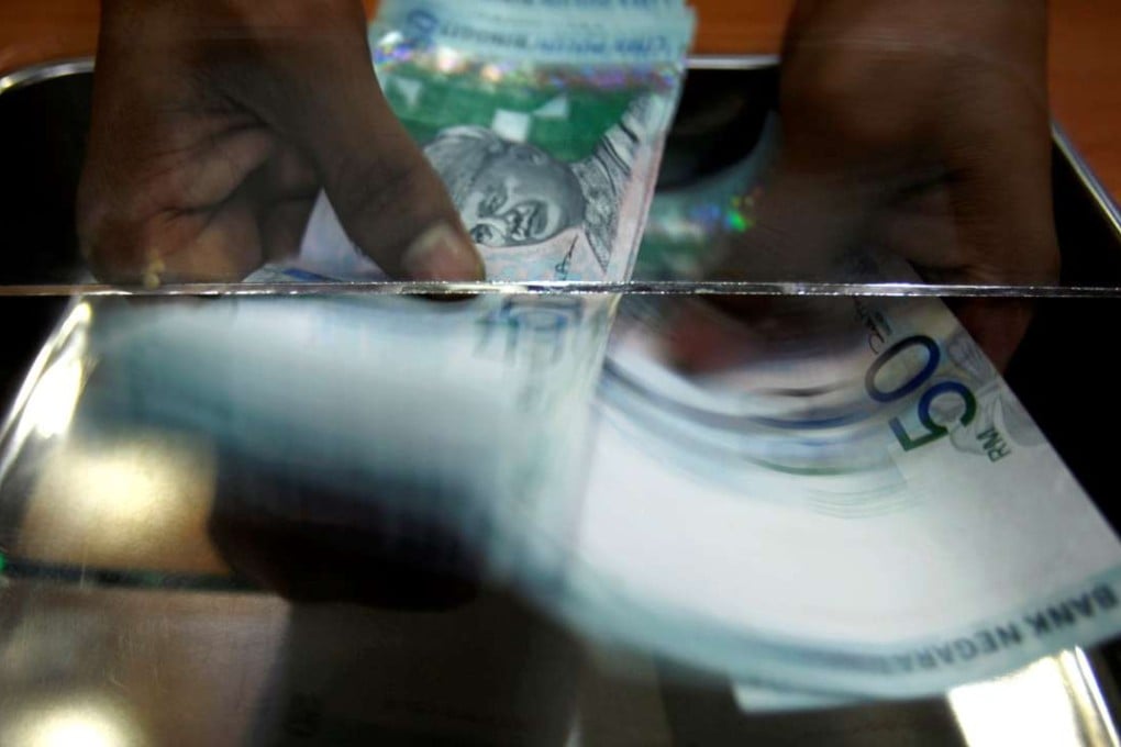 A money changer counts Malaysian ringgit at a shop in Putrajaya outside Kuala Lumpur. The country’s Central Bank warned of a crackdown to ensure stability in the currency. Photo: Reuters