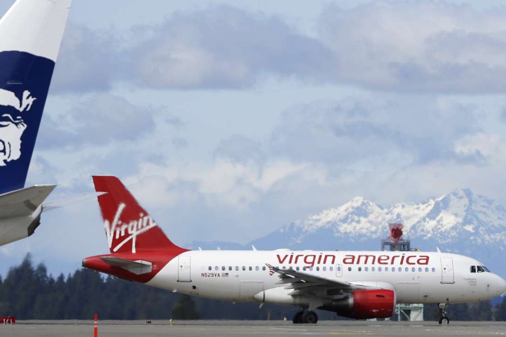 A Virgin America plane taxis past an Alaska Airlines plane waiting at a gate at Seattle-Tacoma International Airport in Seattle. Alaska said Wednesday, March 22, 2017, that it will retire the Virgin brand, probably in 2019. Photo: AP