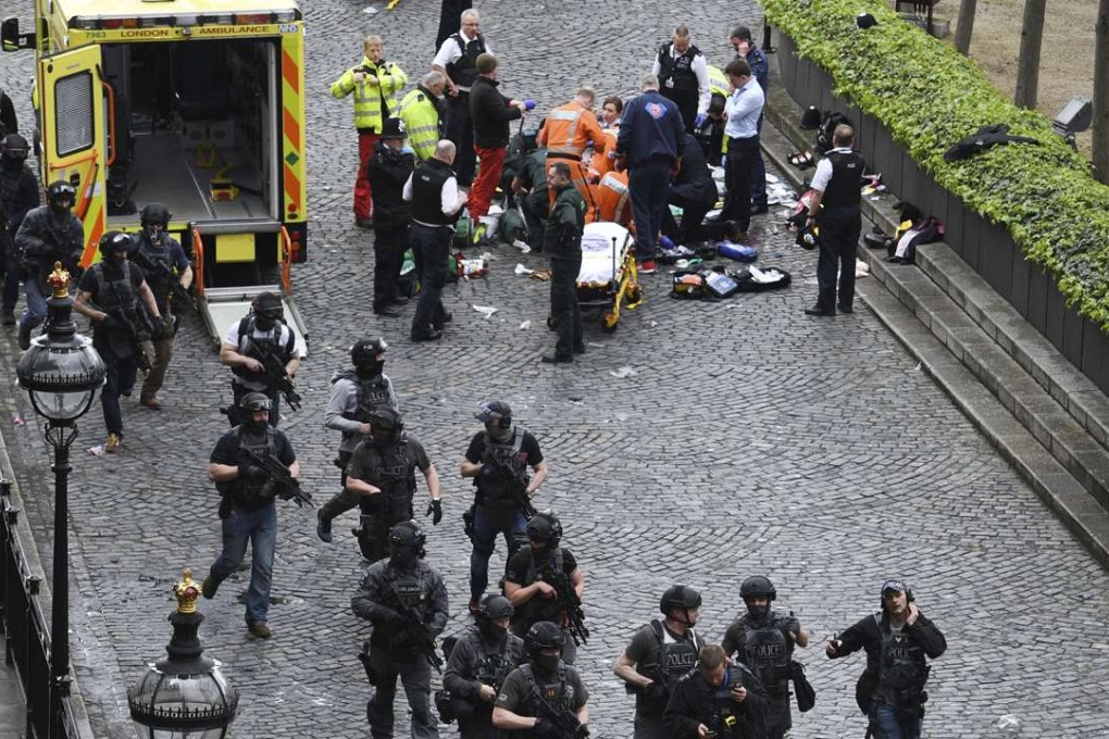 Armed police walk past emergency services attending to injured people outside the Houses of Parliament in London on Wednesday. Photo: AP