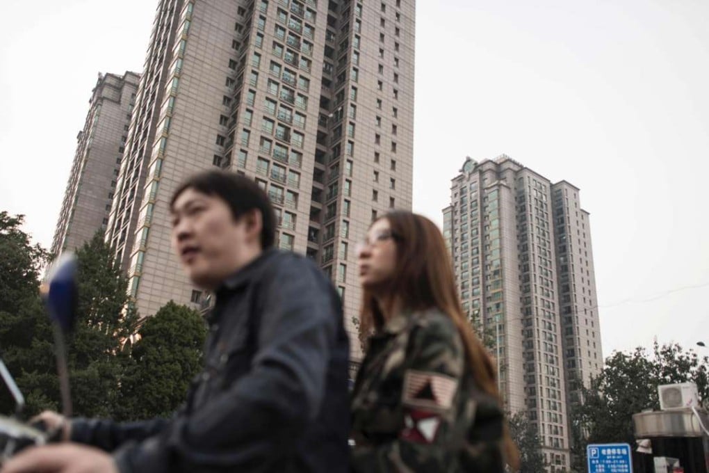 A file picture of a man and woman riding past a residential luxury home complex in Beijing. Photo: AFP