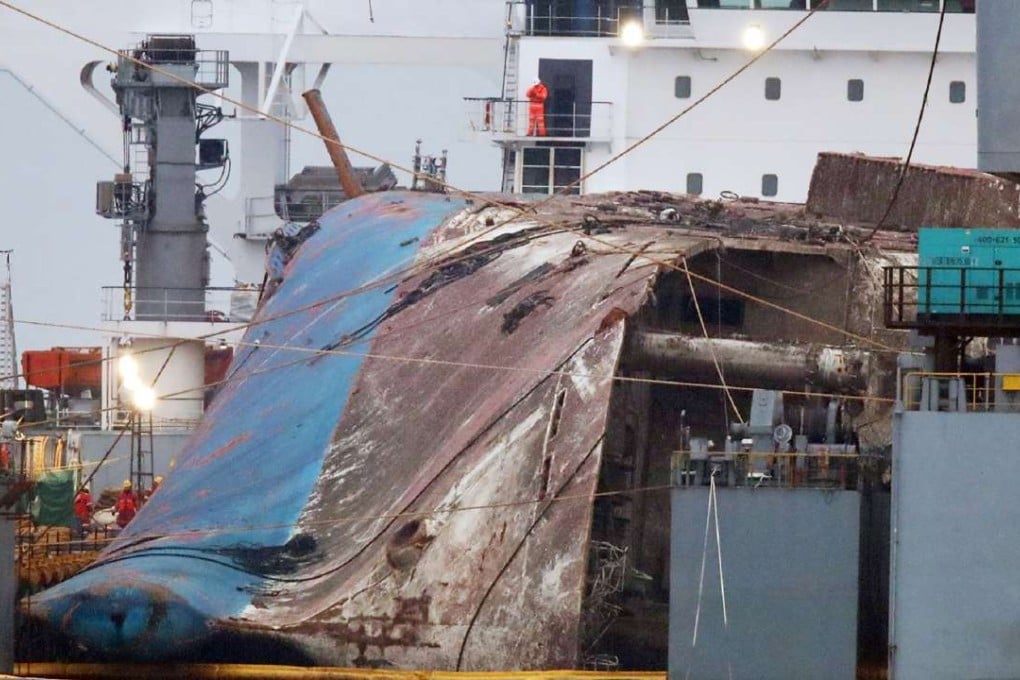 The wreck of the Sewol ferry tied between two barges is placed onto a submersible vessel. Photo: AP