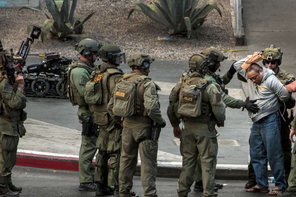 A suspect surrenders to SWAT officers after being barricaded for many hours on a bus after a fatal shooting. Photo: AP