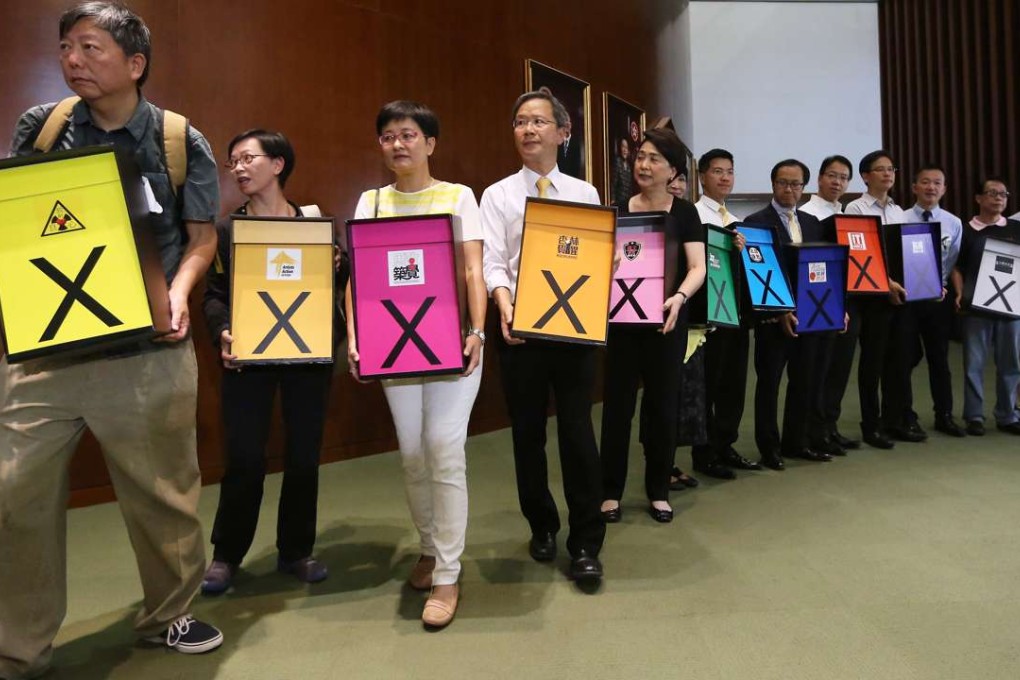 Pan-democrat lawmakers hold signs indicating their stance as they enter the Legislative Council chamber ahead of a debate on the electoral reform proposal, in Tamar on June 17, 2015. The reform package was rejected the following day. Photo: Sam Tsang