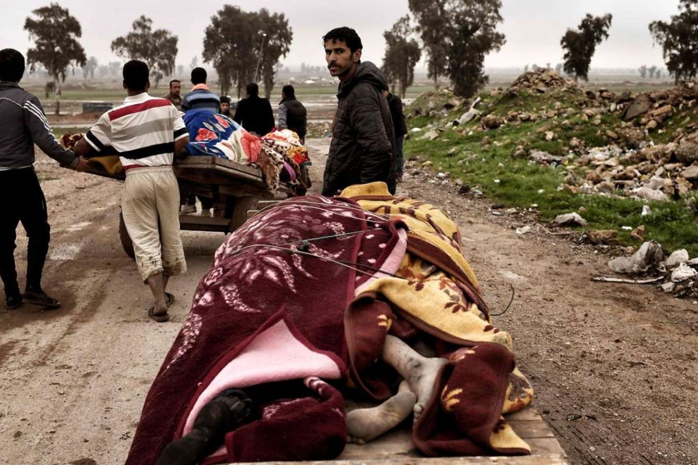 Relatives cart away the bodies of residents of Mosul who were killed in an airstrike on March 17 in which dozens of civilians were killed. Photo: AFP