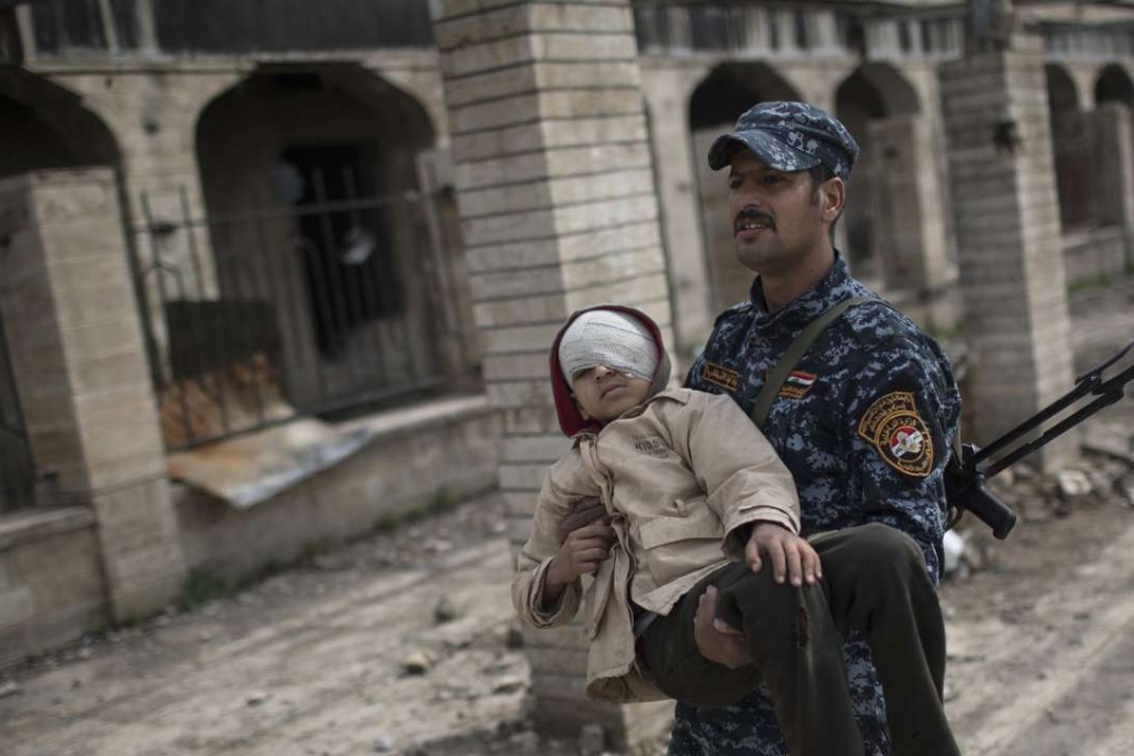 A federal police officer carries an injured boy through a destroyed train station during fighting between Iraqi security forces and Islamic State militants, on the western side of Mosul, Iraq. A suicide truck bombing killed 15 people in the Iraqi capital of Baghdad. Photo: AP