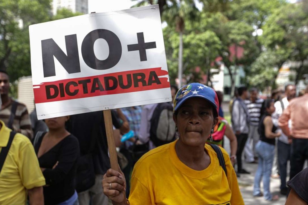 A woman carries a sign that reads ‘No Dictatorship’ during a protest in Caracas, Venezuela, as several protests broke out after a Supreme Court ruling took power from congress raising fear of a dictatorship. The ruling is being condemned by opponents of President Nicolas Maduro and foreign governments. Photo: EPA