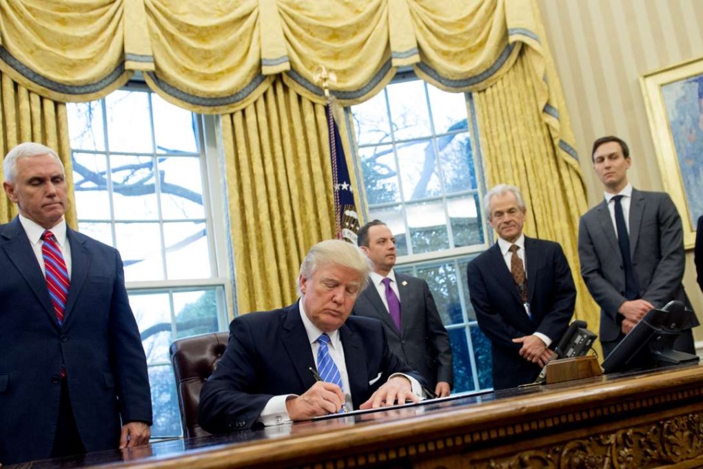 US President Donald Trump signs an executive order watched by,standing, from left, Vice President Mike Pence, Chief of Staff Reince Priebus, National Trade Council Advisor Peter Navarro, Senior Advisor Jared Kushner and Senior Policy Advisor Stephen Miller in the Oval Office on January 23. Photo: AFP