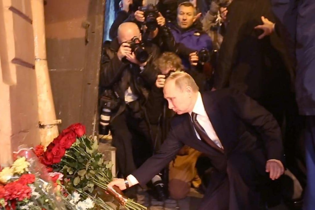 Russian President Vladimir Putin places flowers in memory of victims of the blast in the St Petersburg metro outside Technological Institute station. Photo: AFP