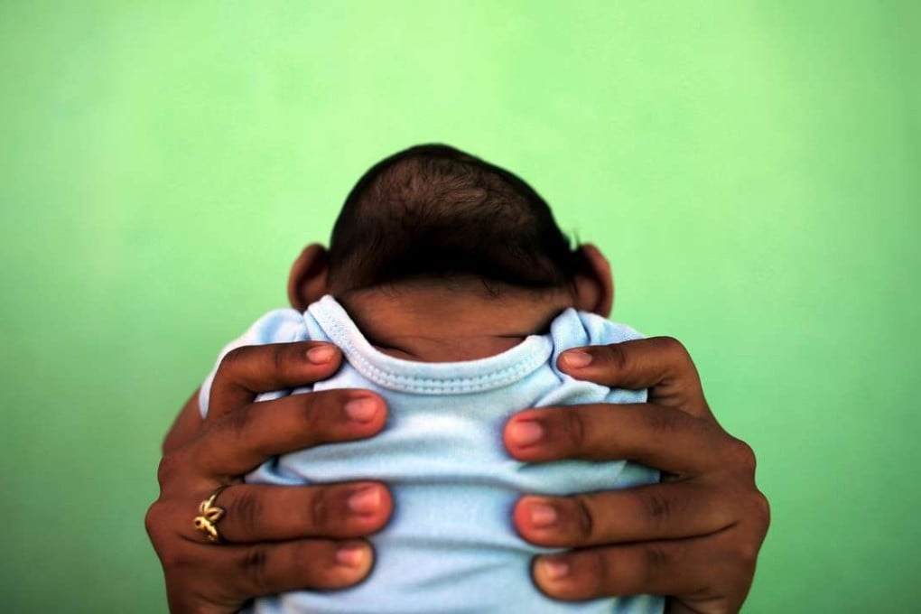 A mother holds her four-month-old son, born with microcephaly, in front of their house in Olinda, near Recife, Brazil. Photo: Reuters