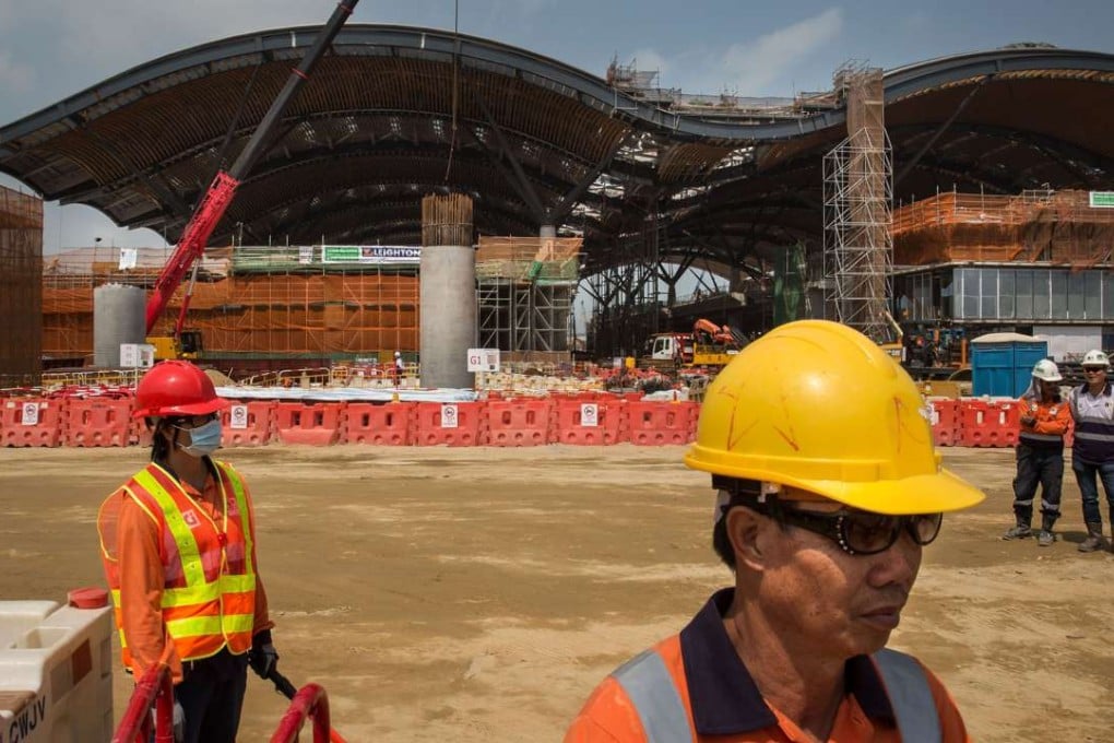 Workers stand near the Hong Kong boundary crossing facilities building that is part of the Hong Kong-Zhuhai-Macau bridge project. In the latest accident to hit the project, two workers died. Photo: Bloomberg