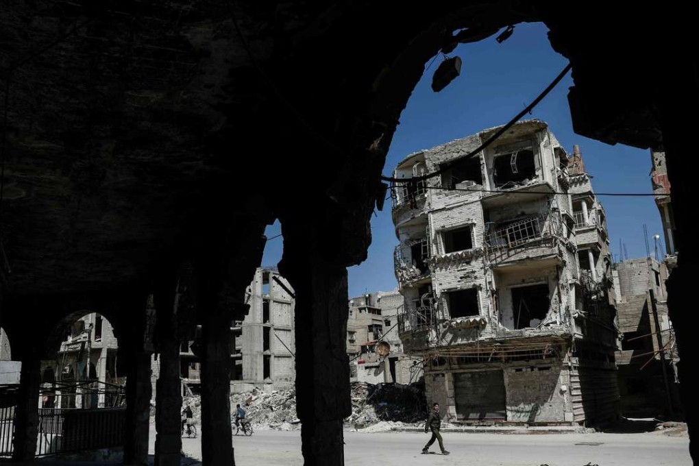 Syrians walk past damaged buildings on April 7 in the rebel-held town of Douma, on the eastern outskirts of Damascus. Photo: AFP