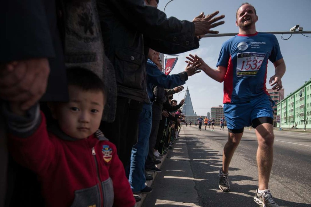 Competitors of the Pyongyang Marathon run past spectators, before the Ryugyong hotel (rear C) in central Pyongyang. Photo: AFP