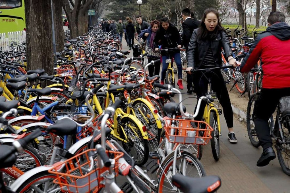 People riding yellow bicycles from bike-sharing company Ofo try to pedal along a pavement crowded with bicycles from bike-sharing companies Ofo, Mobike and Bluegogo in Beijing last month. (March) Photo: AP