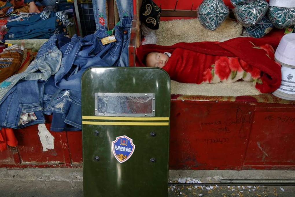 A child sleeps as a riot shield leans on a stall at the bazaar in Hotan, Xinjiang late last month. Photo: Reuters