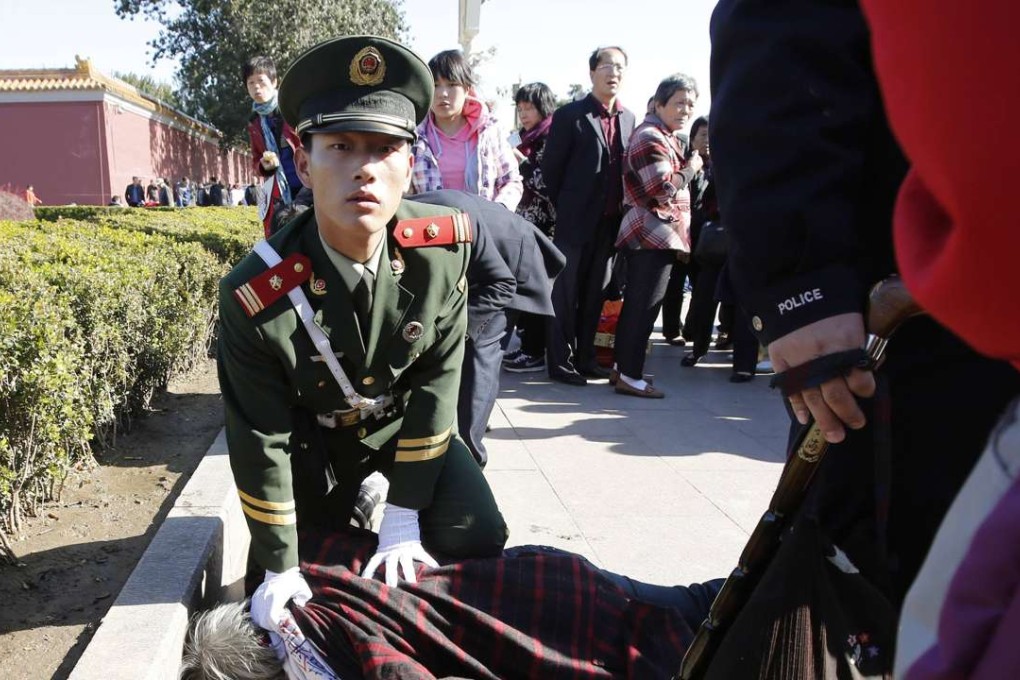 In this file photo from October 2013, a paramilitary policeman detains a woman who threw papers believed to be her petition papers near the main entrance of the Forbidden City in Beijing. Photo: Reuters