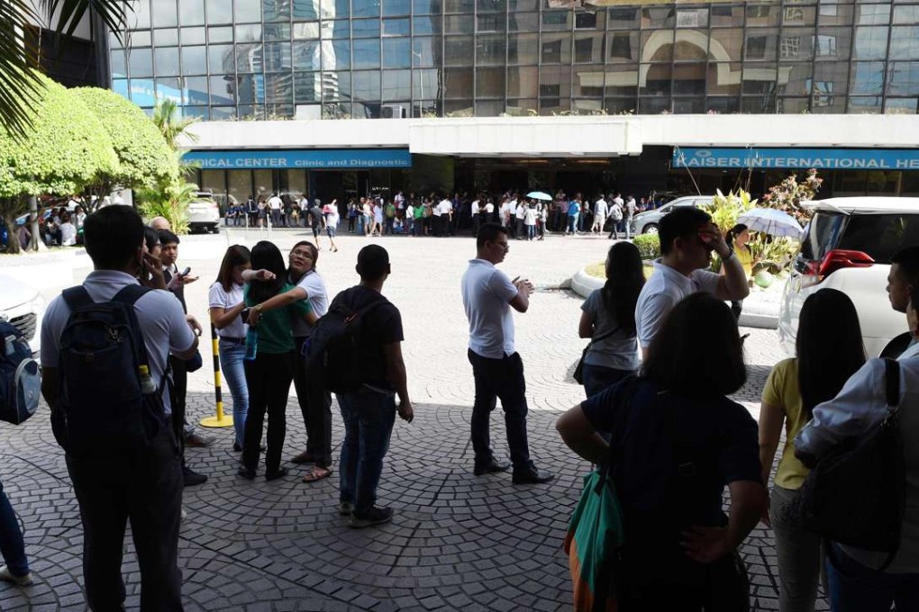 Office workers stand on the grounds of an office building in the financial district of Makati on April 8, 2017, after a 5.7 magnitude earthquake rocked the Philippines. Another quake hit Mindanao island on Wednesday, April 12. Photo: AFP