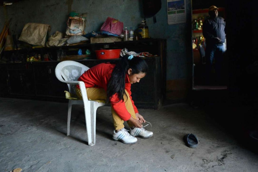 Young Nepalese golfer Pratima Sherpa ties her shoelaces as she prepares for a round of golf in Kathmandu. Photo: AFP