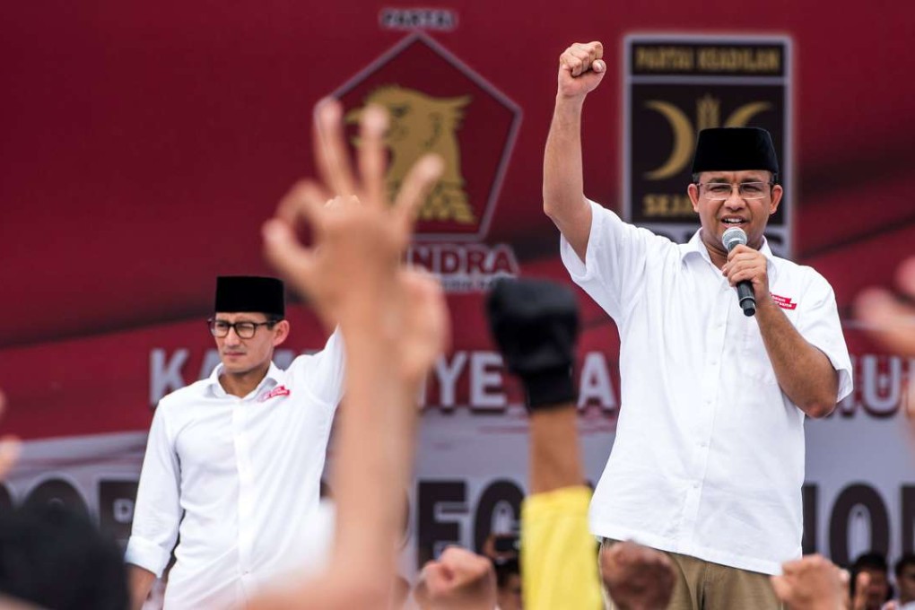 Anies Baswadan, right, a gubernatorial candidate in Jakarta, and his deputy, Sandiaga Uno, stand in front of their supporters while campaigning. Efforts to make the election about the economy have been drowned out by religious controversy. Photo: Reuters