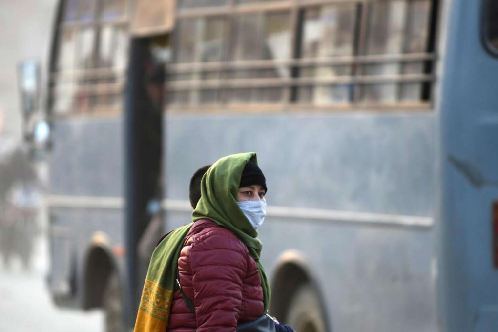 A woman covers her face with a mask as she walks along a dusty road in Kathmandu. Photo: AFP