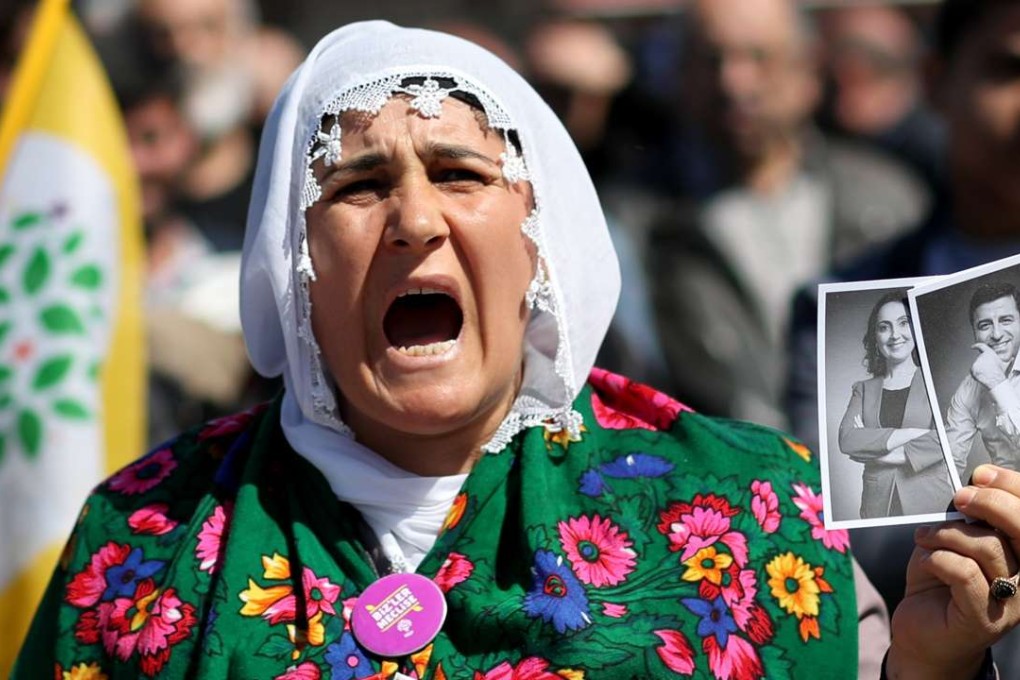 A supporter of the pro-Kurdish People’s Democratic Party holds pictures of party co-leaders who were arrested as part of a terror investigation, during a “Vote No” rally in Istanbul on April 13. Photo: EPA