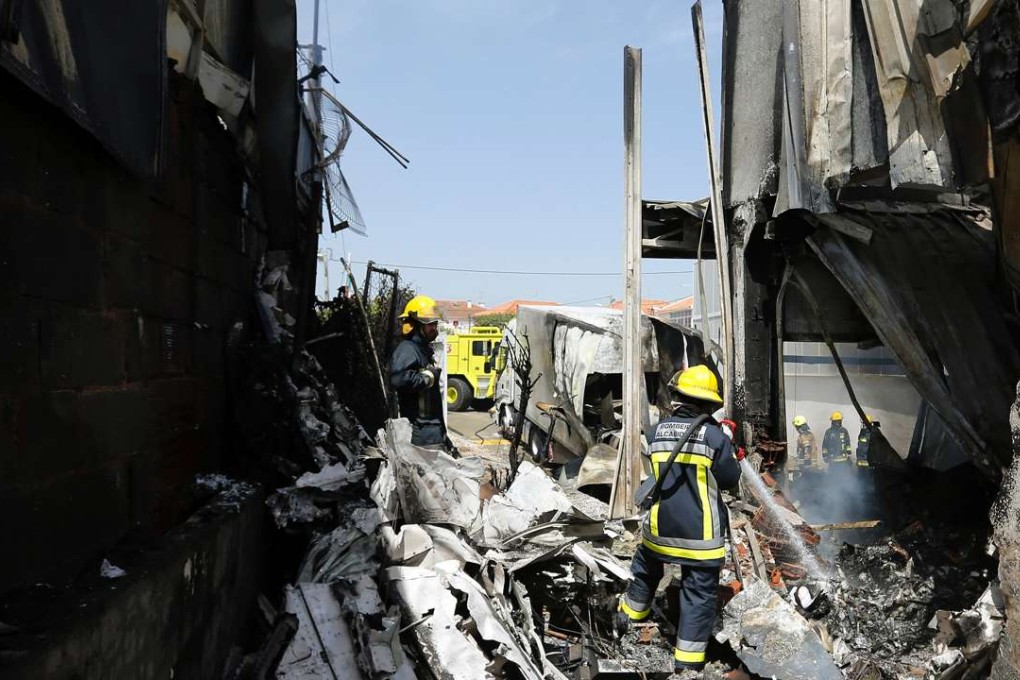 Firefighters work to extinguish the remains of a fire after a plane crashed into a supermarket warehouse in the Lisbon suburbs on Monday. Photo: AFP