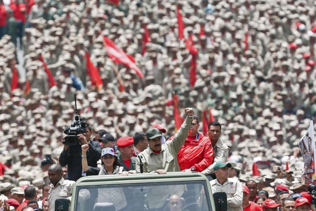 Venezuelan President Nicolas Maduro, saluting next to his wife Cilia Flores, arrives at celebrations for the seventh anniversary of the Bolivarian Militia in Caracas on Monday. Photo: AFP