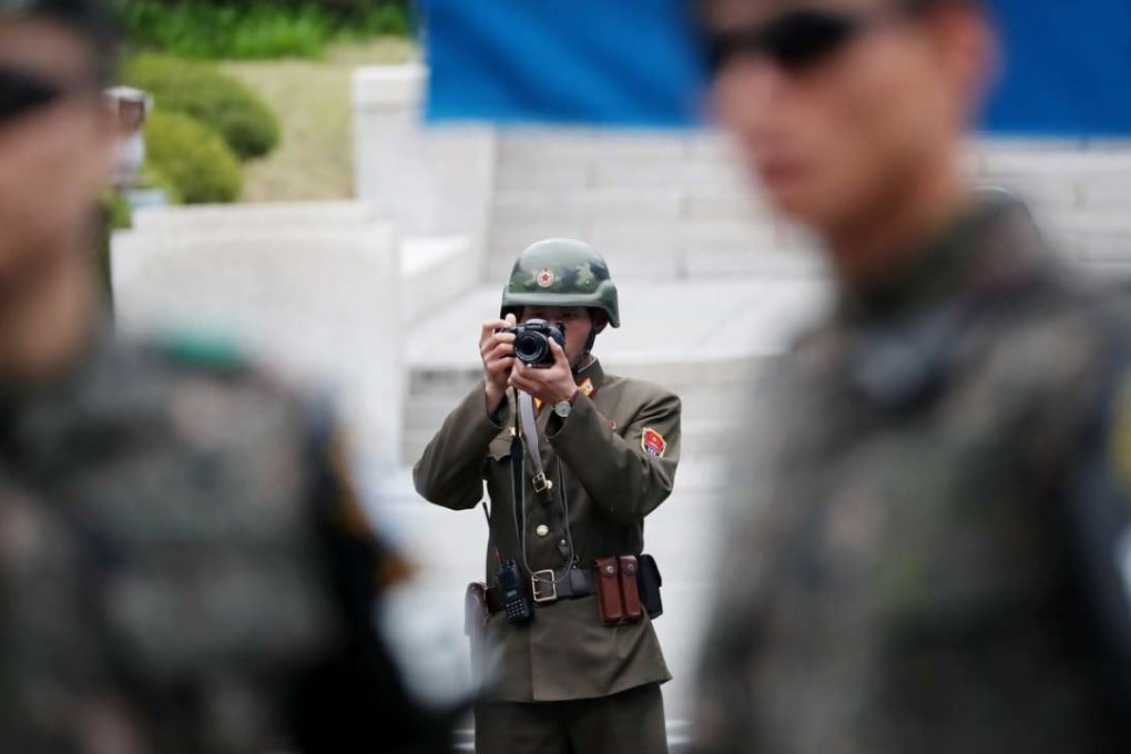 A North Korean soldier takes a photograph as South Korean soldiers stand guard at the truce village of Panmunjom in the Demilitarized Zone in Paju, South Korea. Photo: Bloomberg