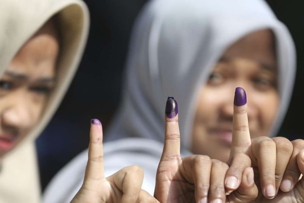Muslim women show their ink-stained fingers after voting during the run-off election in Jakarta, Indonesia. Residents of the Indonesian capital are electing a governor after a polarising campaign that undermined the country's reputation for practising a tolerant form of Islam. Photo: AP