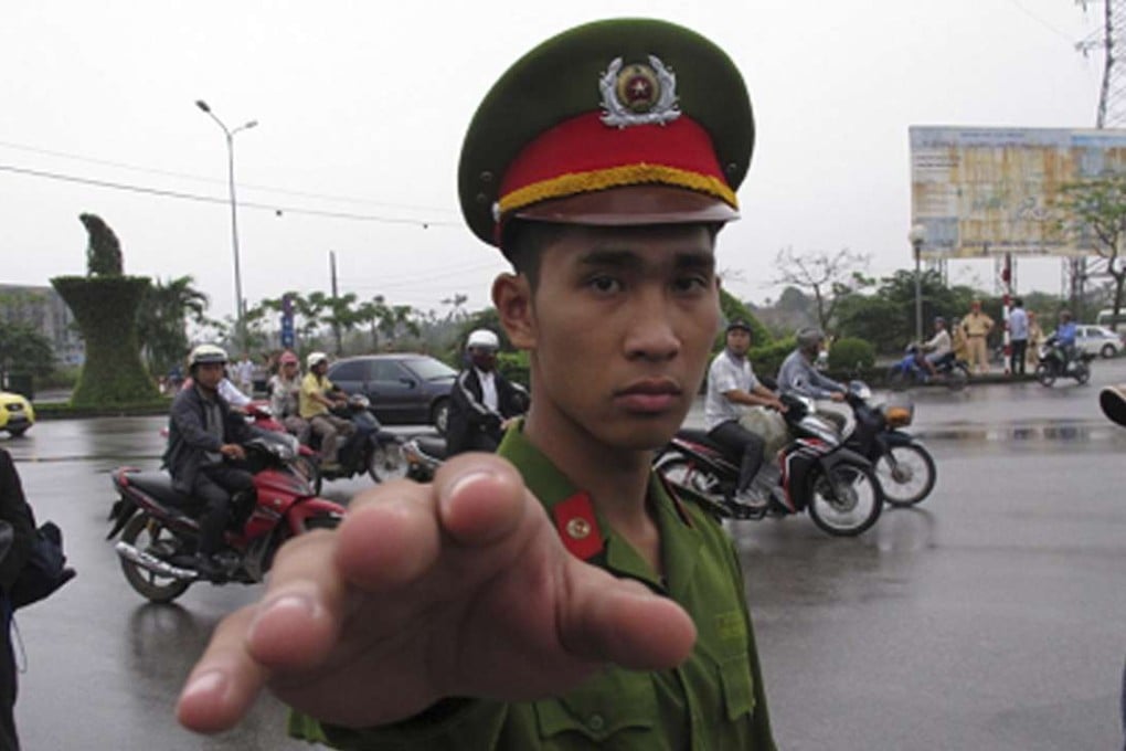 A Vietnamese police officer gestures toward a photographer in 2013. Photo: AP