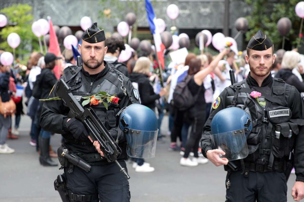 Policemen bearing flowers stand during a rally organized by the “Angry Policemen's Wife” (FFOC) in support of French policemen, near the esplanade of the Champs de Mars. Photo: AFP