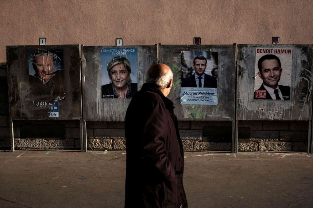 A man passes by campaign posters for the French presidential election, on official billboards. Photo: AFP