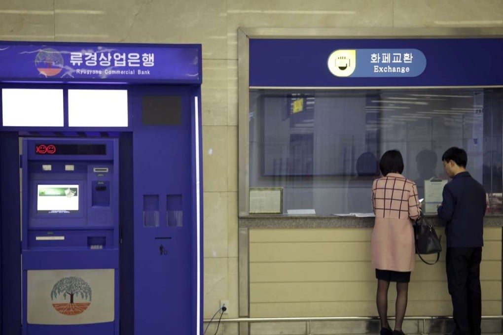 A man and woman stand at a counter next to a Ryugyong Commercial Bank automated teller machine at the Sunan International Airport in Pyongyang, North Korea. Photo: AP