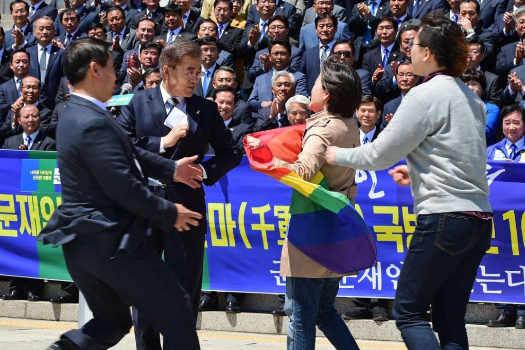 A supporter of the LGBT community carrying a rainbow flag approaches presidential candidate Moon Jae-in. Photo: EPA