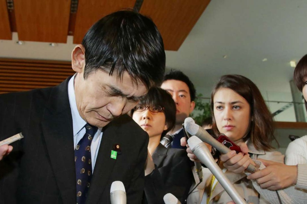 Surrounded by reporters, Japan's Disaster Reconstruction Minister Masahiro Imamura bows after submitting his resignation to Prime Minister Shinzo Abe. Photo: AFP