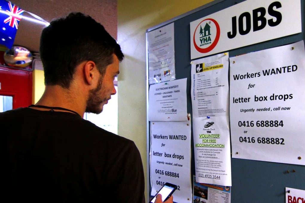 A man uses his phone to record job ads posted on a noticeboard at a backpacker hostel in Sydney last May. Photo: Reuters