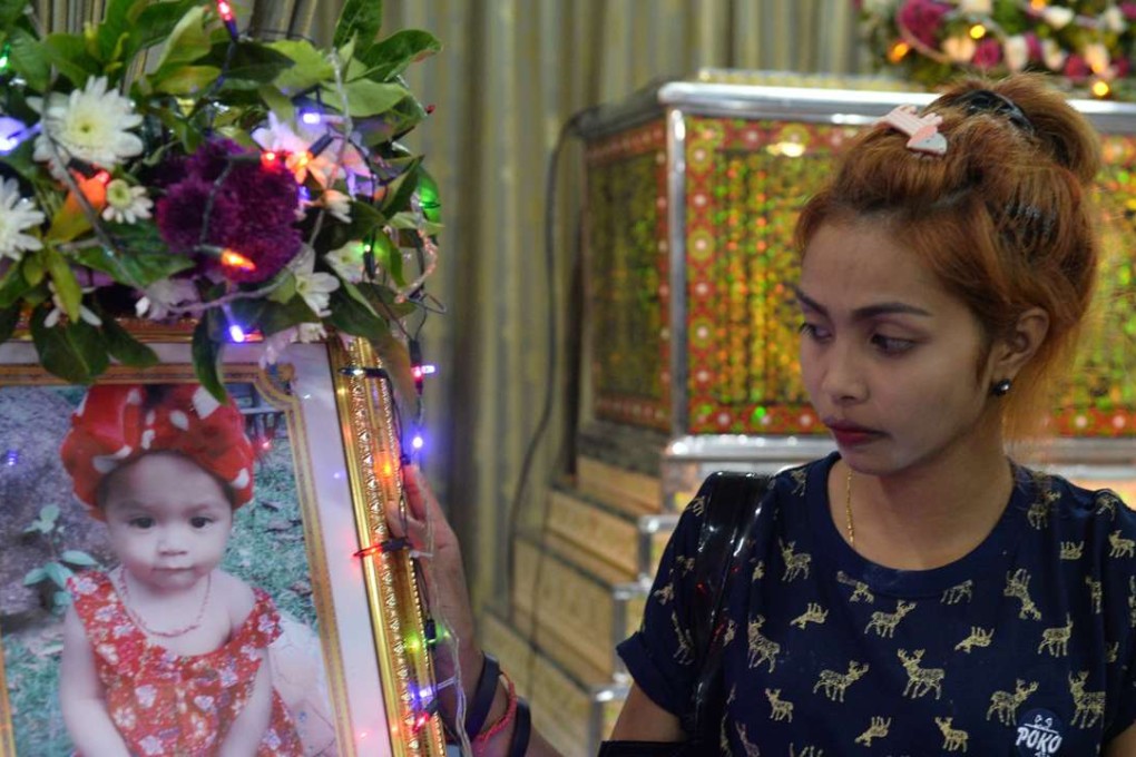 Jiranuch Trirat, mother of an 11-month-old girl killed by her father who broadcast the murder on Facebook, next to a picture of her daughter at a temple in Phuket. Photo: Reuters