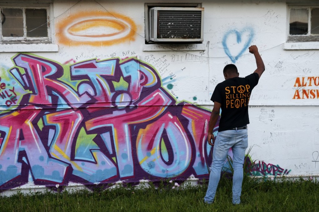 Damon Brumfield, a student at Southern University of Baton Rouge, poses while his friends take photos, in front of a mural honouring Alton Sterling in Baton Rouge Louisiana on Tuesday. Photo: AP