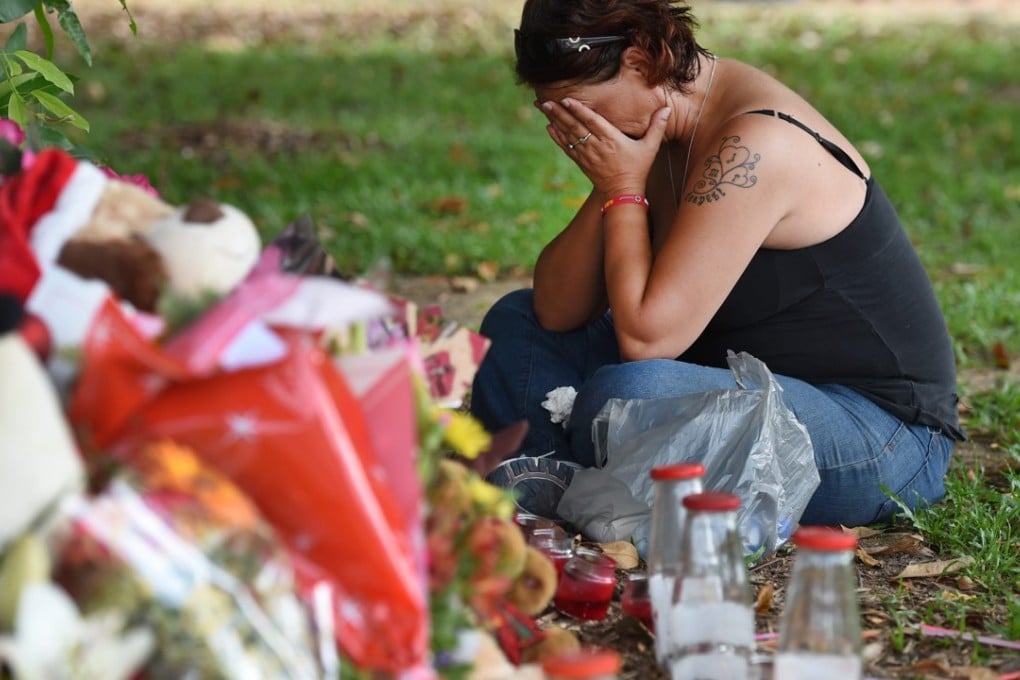 A neighbour views a floral tribute near a house where eight children were stabbed to death in the Cairns suburb of Manoora in December 2014. Photo: EPA