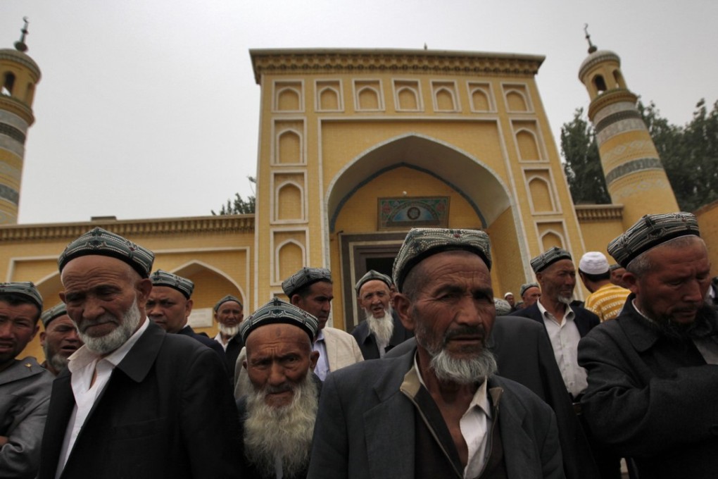 Uygur men stand outside the Id Kah Mosque after Friday prayers in Kashgar in July 2014. Photo: EPA